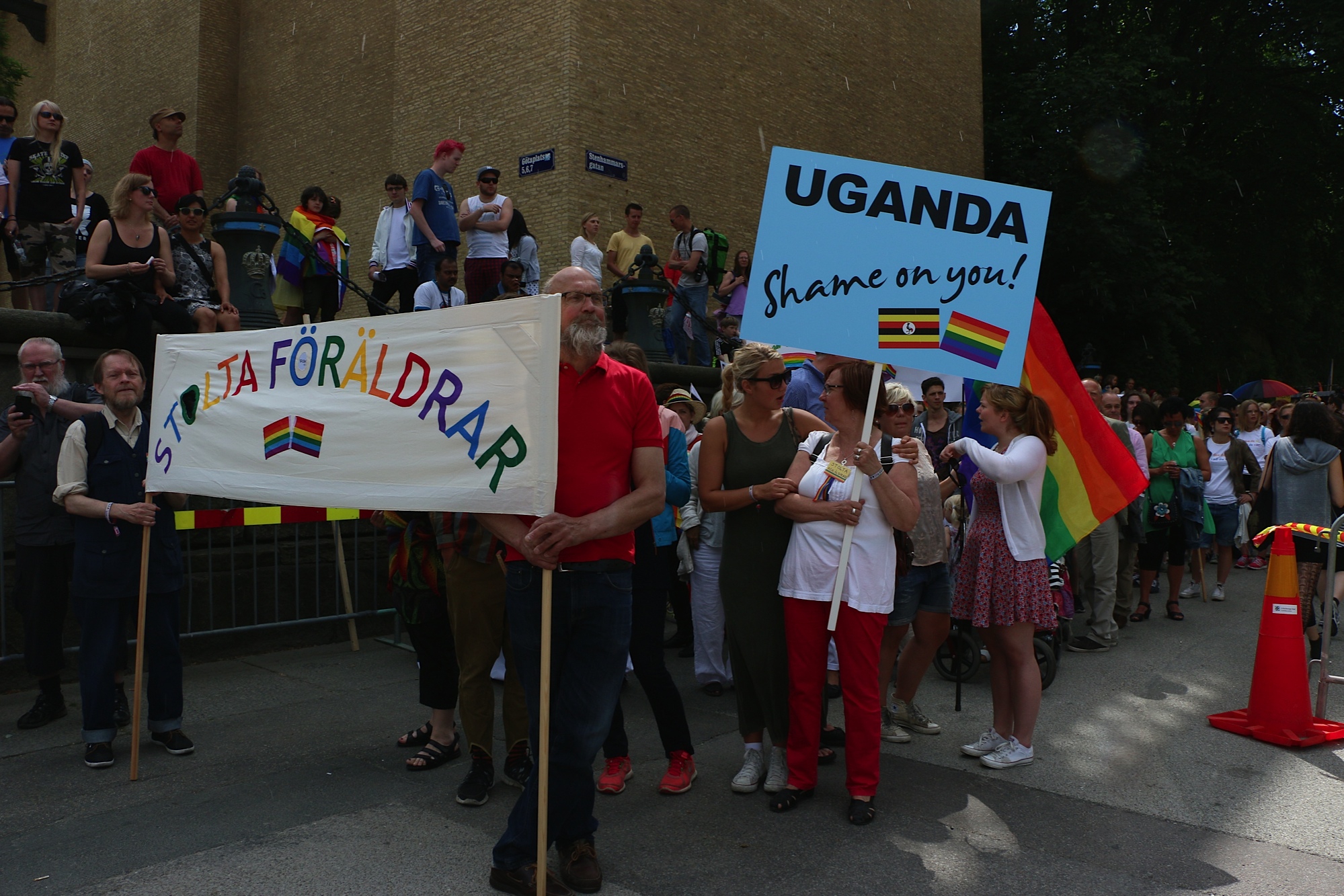 stolta föräldrar i parad med stor färgglad banderoll som det står stolta föräldara på